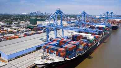 A photograph of a cranes unloading containers from an ocean vessel.