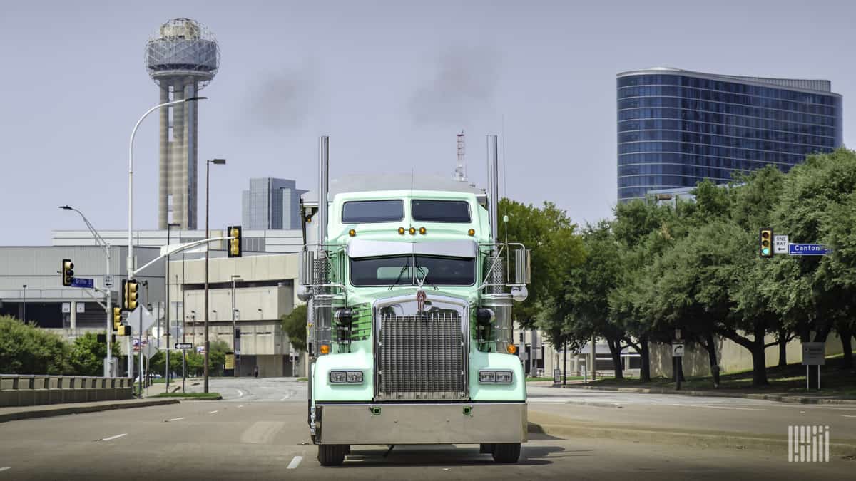 Front view of sea green truck driving on empty city street