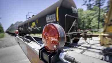 A photograph of a tank car by a rail crossing.