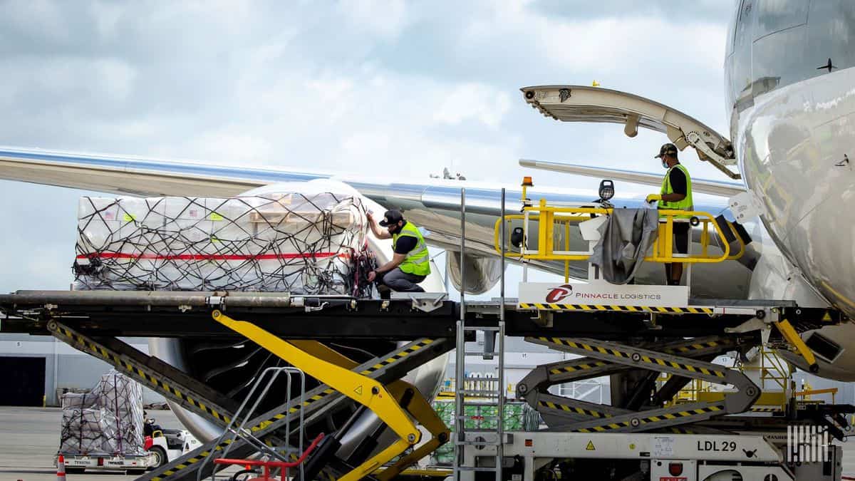 Cargo pallets on a lift platform being loaded in the side of a large plane. Airlines carried fewer loads in the first six months, but made more money because they could charge much more.