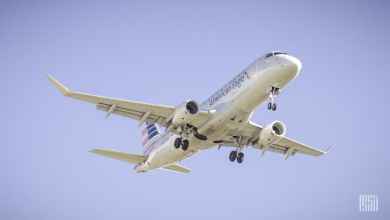 Looking up at a silver plane overhead coming in for landing at airport.