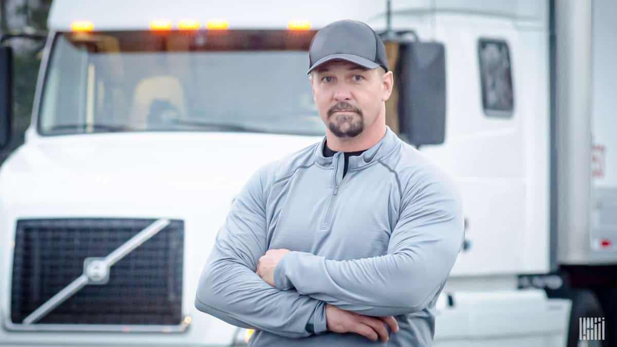 A driver stands in front of his rig. Where will his next load come from?