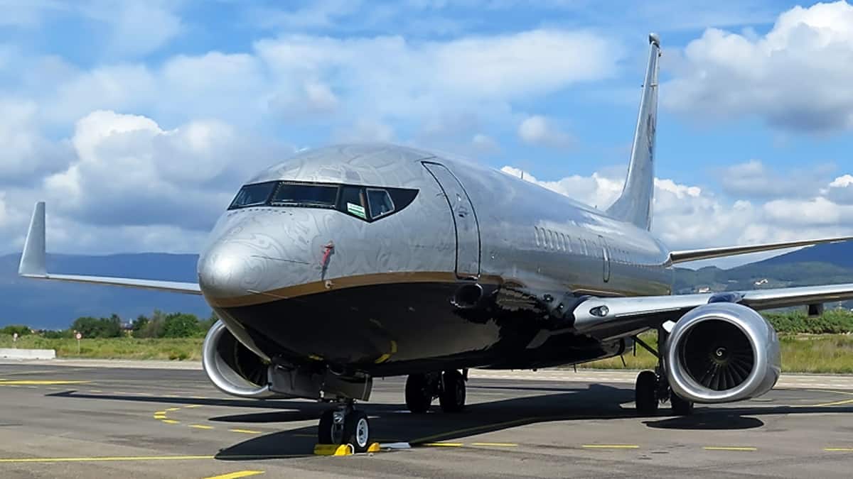 A silver Boeing 737 on the ground, close up view looking at the cockpit from outside.