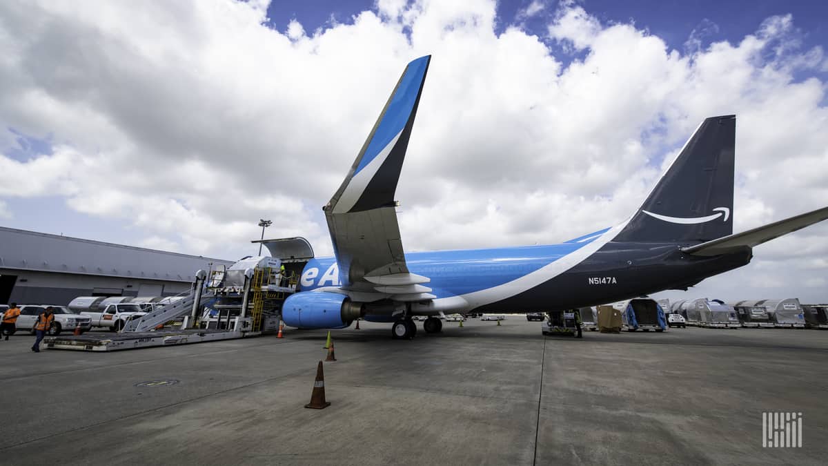 A light/dark blue Amazon Prime jet at the cargo terminal, with wing tips folded up, as viewed from the side. Amazon Air is opening new airport facilities in Hawaii.