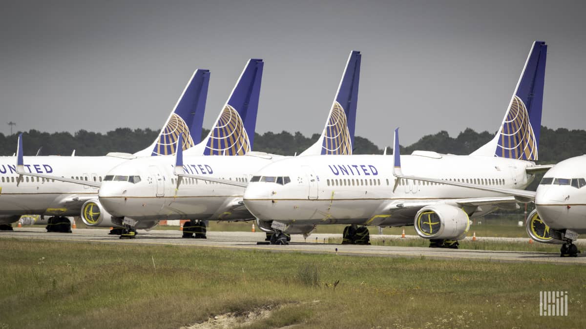 White jets with blue tails from United Airlines lined up on an inactive taxiway at George Bush Intercontinental Airport in Houston. They're in storage.