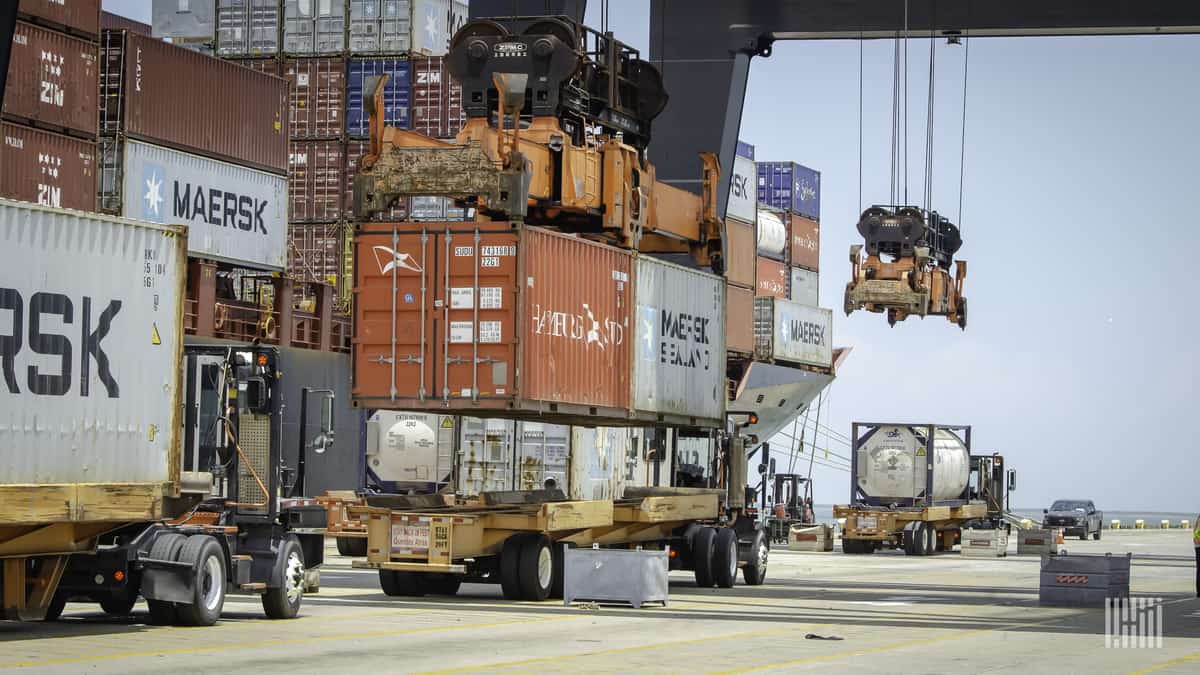 A port's crane removes containers from a flatbed.