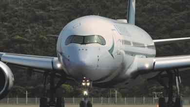 Staring straight ahead at a big white jet. from the front. Cathay Pacific is storing planes in sunny climates.