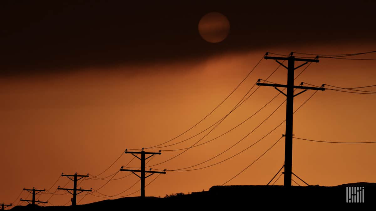 Hot sun across the sky with power lines along the road.