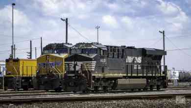 A photograph of a Norfolk Southern locomotive and another freight train locomotive parked at a rail yard.
