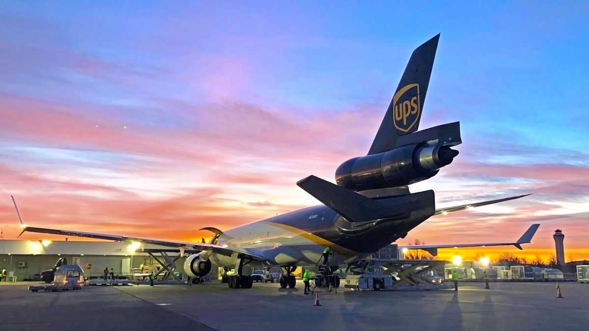 A UPS plane at sunset, view from behind the tail in shadows. UPS is expanding at Kansas City Airport.