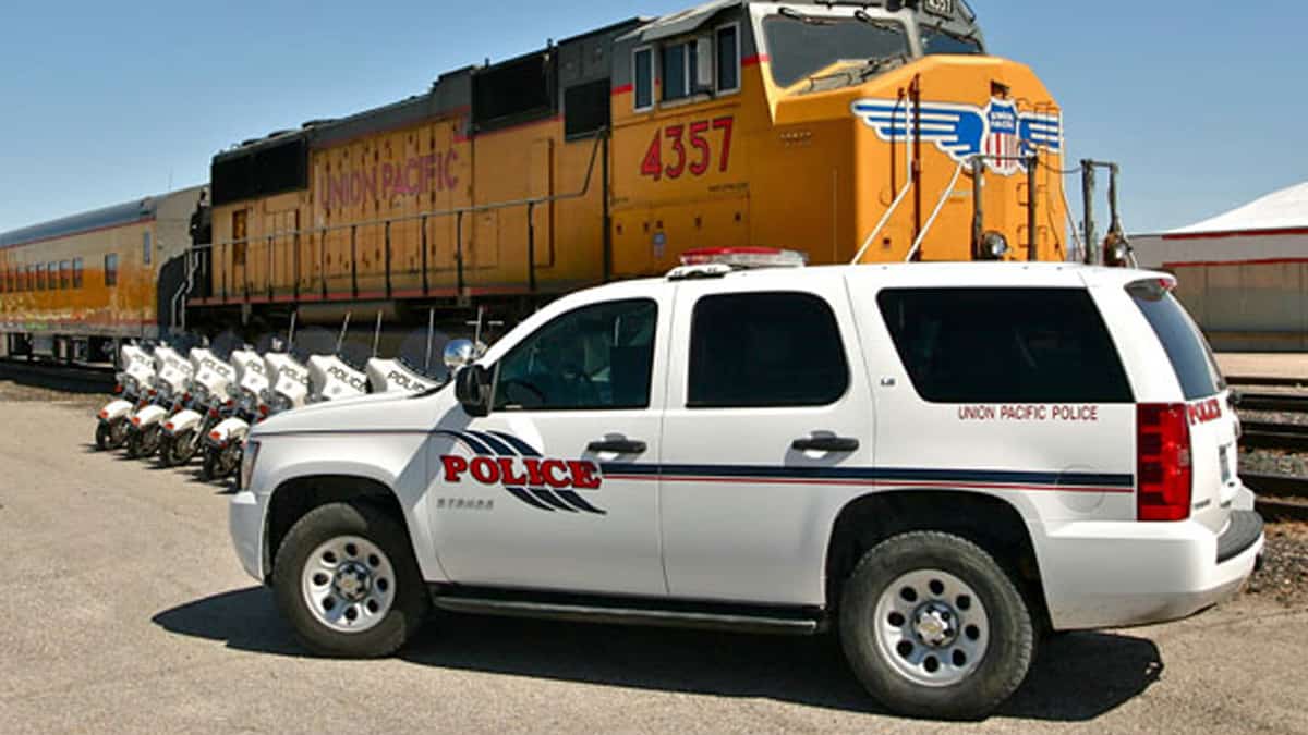 A photograph of a van that says Union Pacific Police on the van. Behind the van is a Union Pacific train.