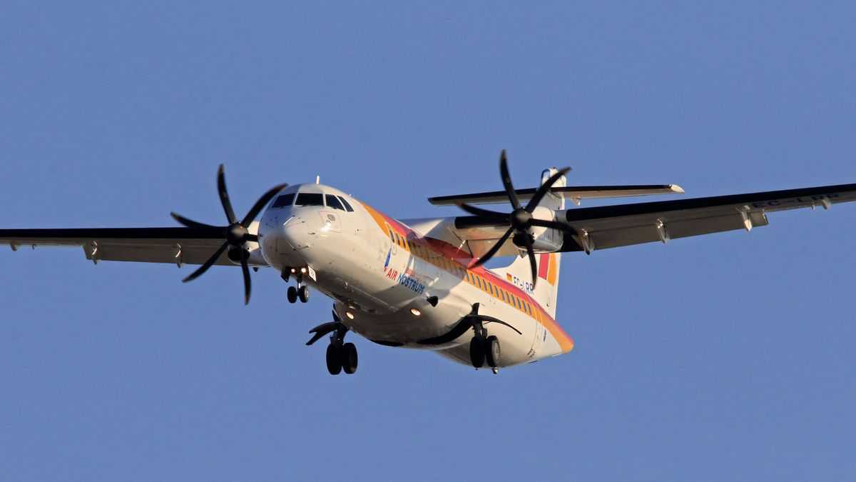 A twin-engine, turboprop plane coming in for landing with wheels retracted. The ATR 72-600 is popular with many regional airlines.