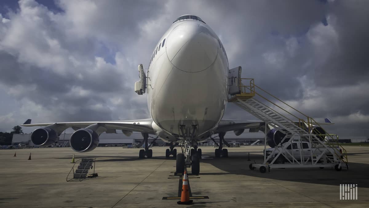 A front-end of jumbo jet looking straight on from nose under sunny sky.