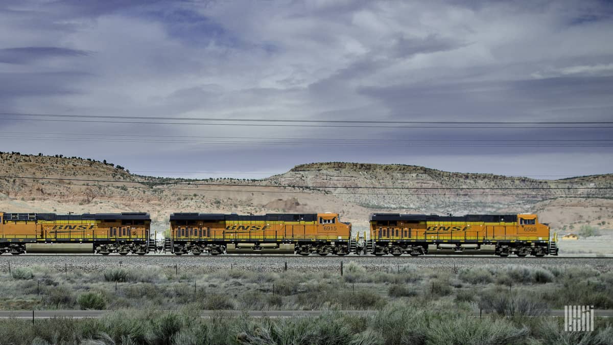 A photograph of a BNSF train traveling along a desert-like mountain pass.