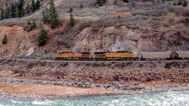 A photograph of a Union Pacific train traveling by a rocky mountainside.