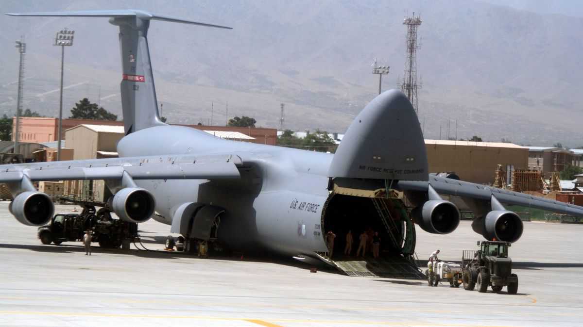 A big military cargo jet with the nose cone lifted up to allow vehicles to drive onboard. The U.S. Air Force has many C-5 cargo planes.