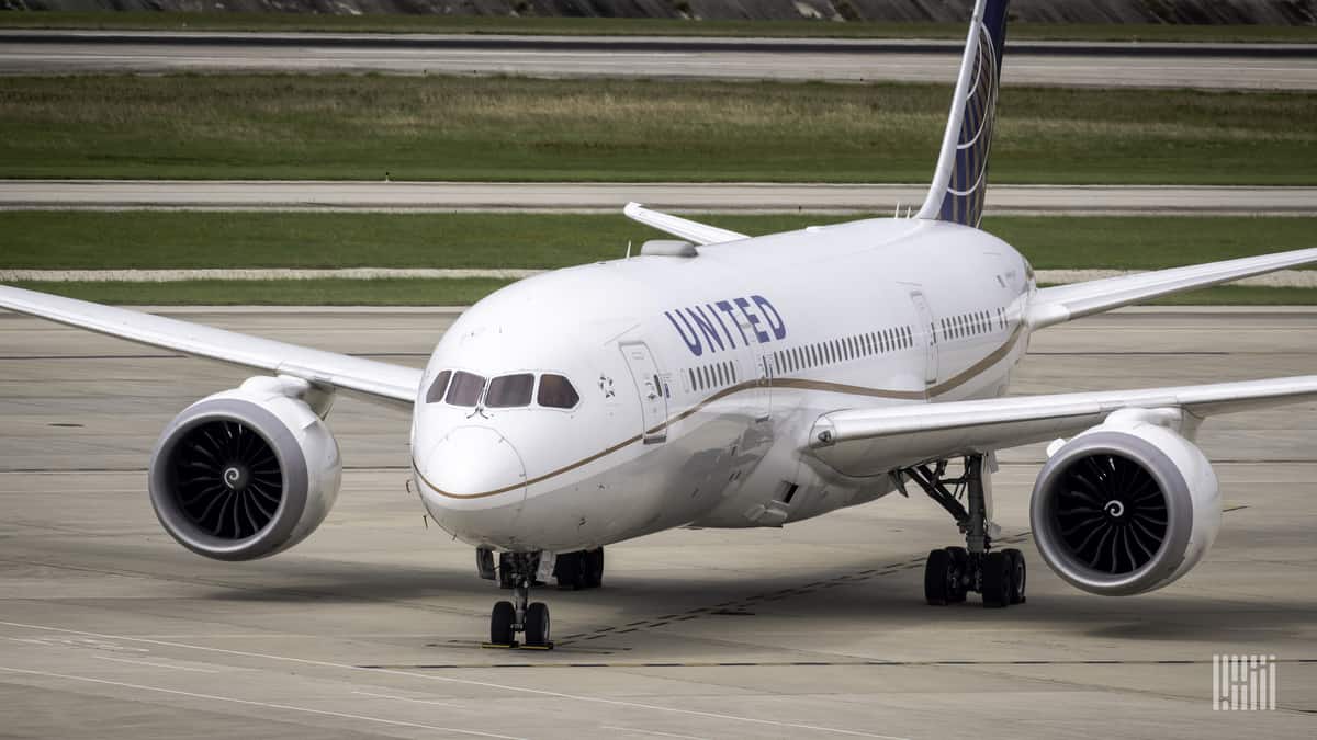 A white United Airlines jet turning on the taxiway at airport.