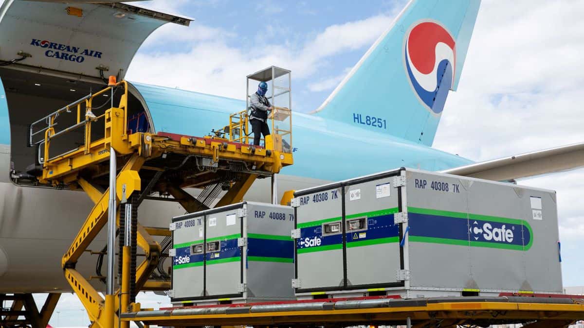Refrigerated containers get lifted onto a light blue cargo plane for Korean Air.