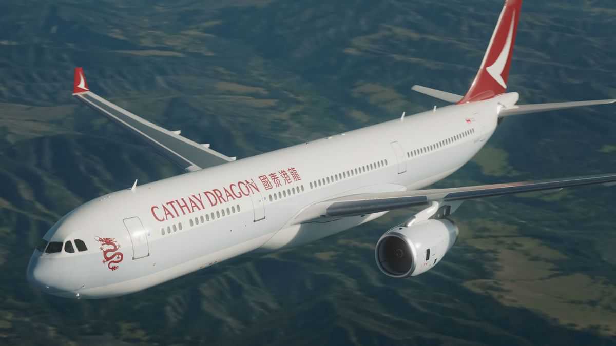 A big white jet with red tail on clear day at high altitude with ground below.