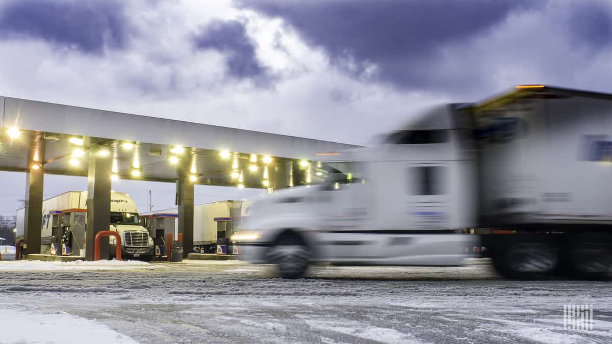 Tractor-trailers at a truck stop on a snowy day.