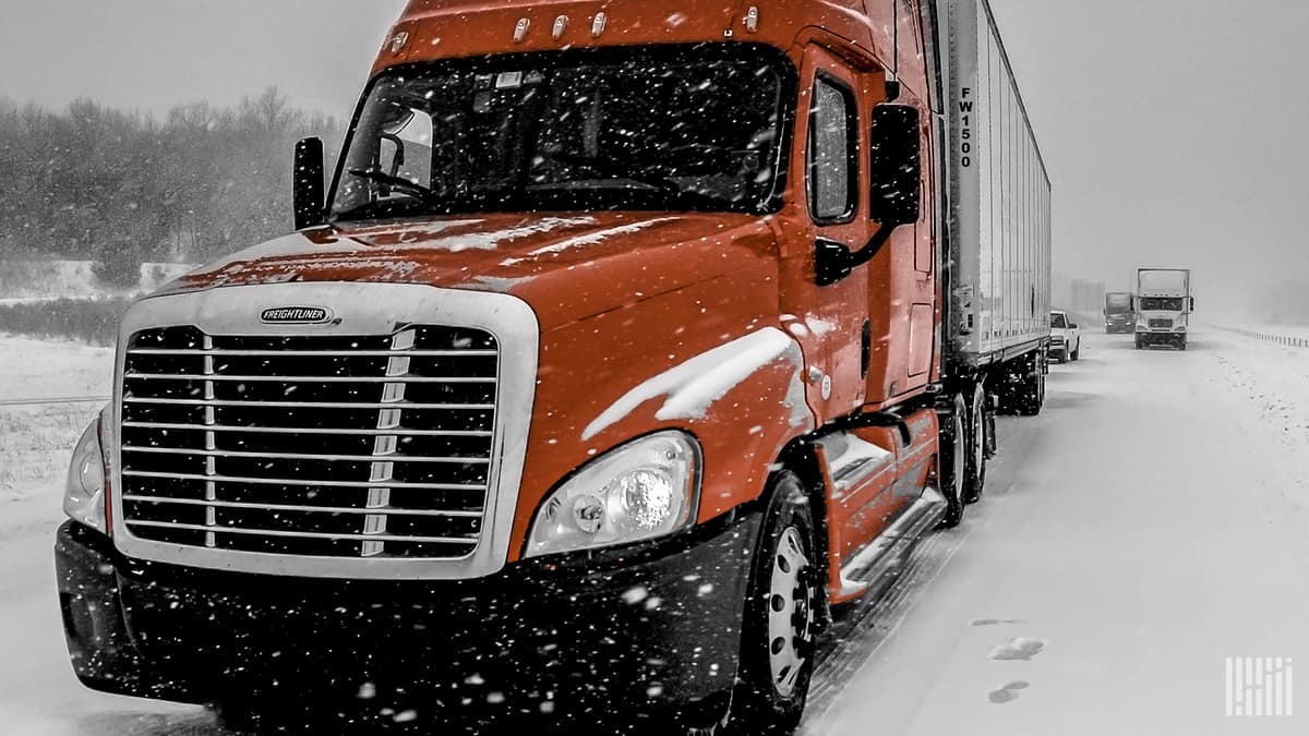 Tractor-trailers stopped on a snowy highway.