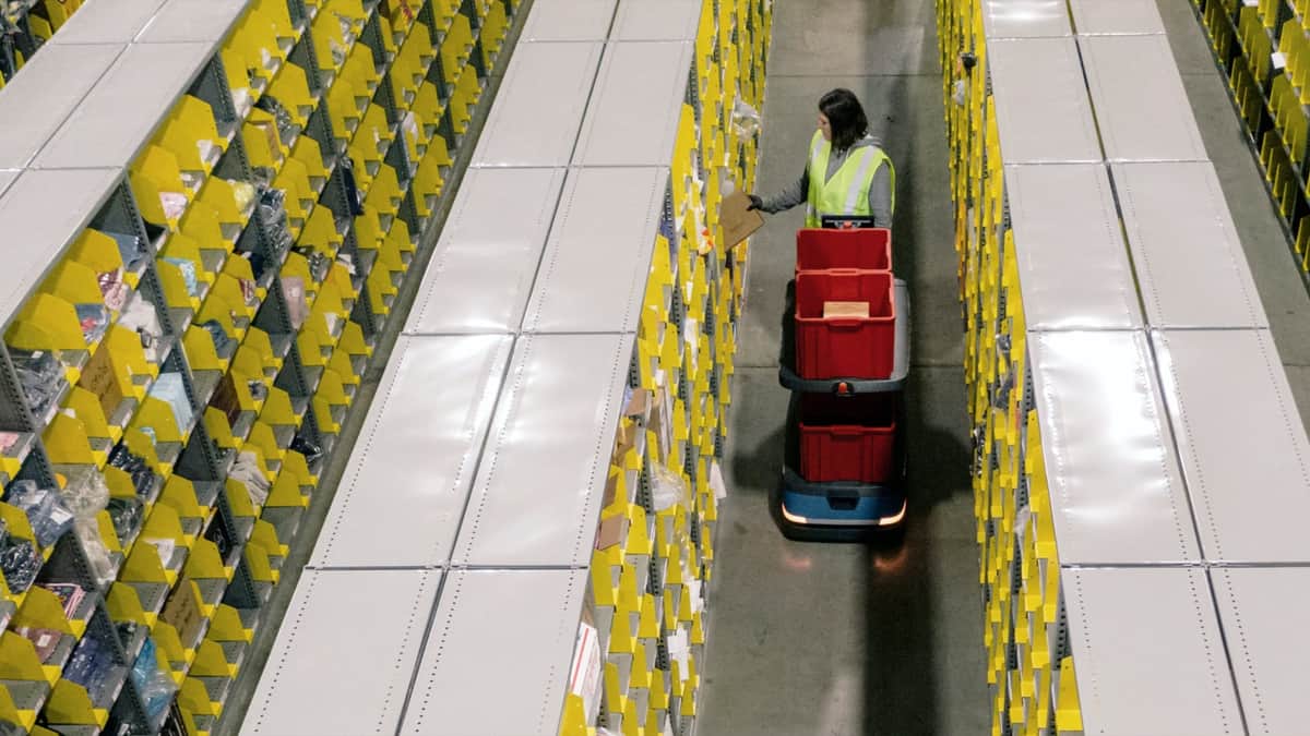 A robot helps a warehouse worker at a Shopify fulfillment facility.