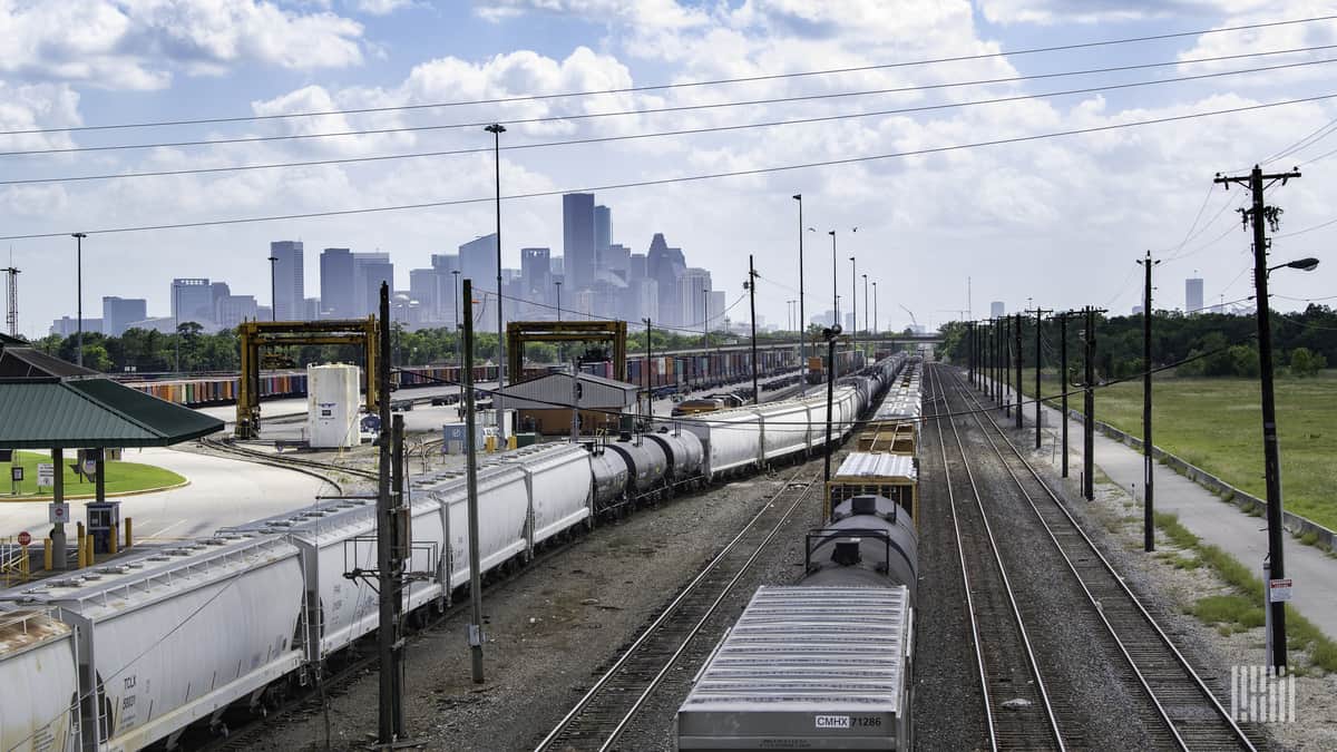 A photograph of a rail yard with city skyscrapers in the background.