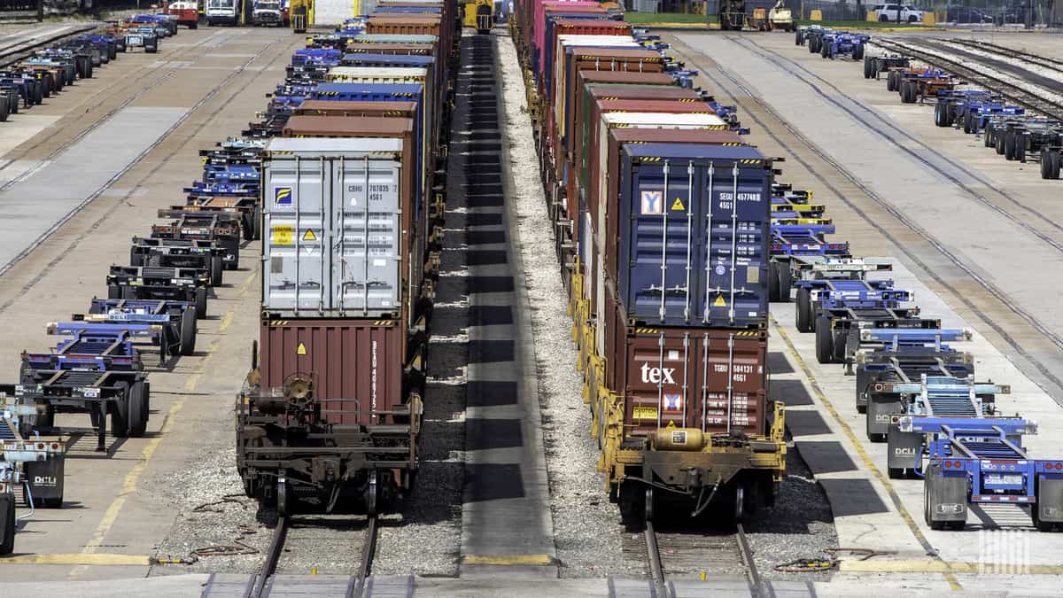 A photograph of intermodal containers and chassis parked in a rail yard.