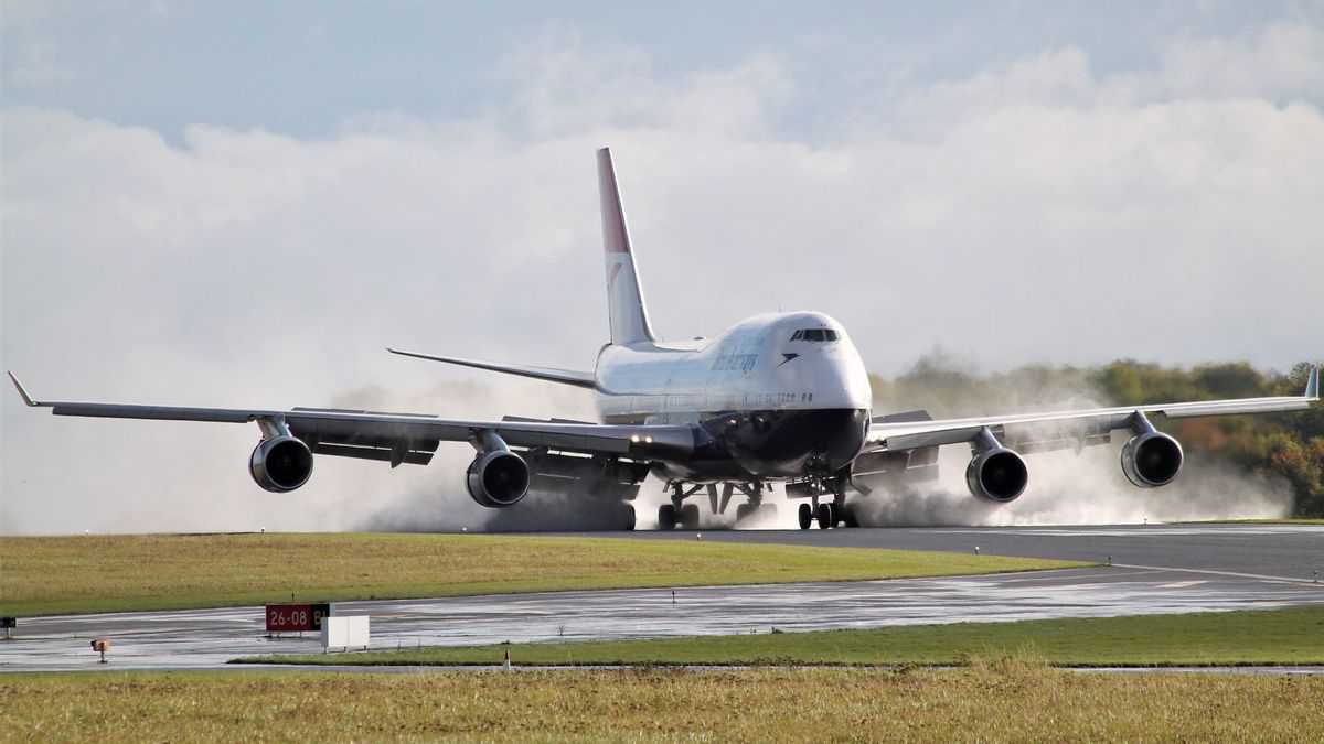 A British Airways 747 touching down on runway with smoke from tires.