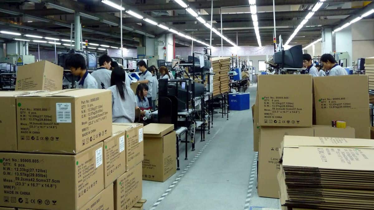 Inside a small Chinese factory assembly line with boxes piled up.
