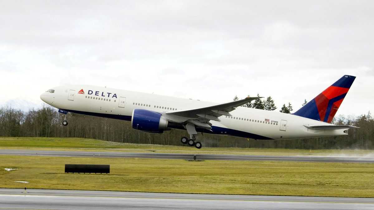 A big white Delta jet with blue tail takes off from runway.