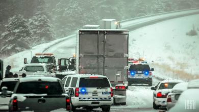 Tractor=trailers and cars in a traffic jam on a snowy highway.