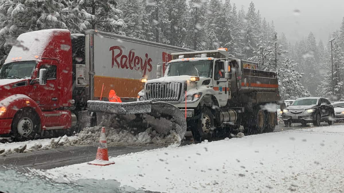 Tractor-trailers and cars in traffic on a snowy road in the Sierra Nevada.