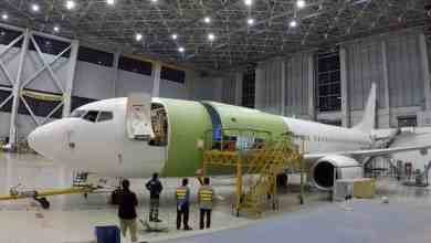 A Boeing 737 in a giant garage where it is being retrofitted with new equipment to carry cargo instead of passengers.
