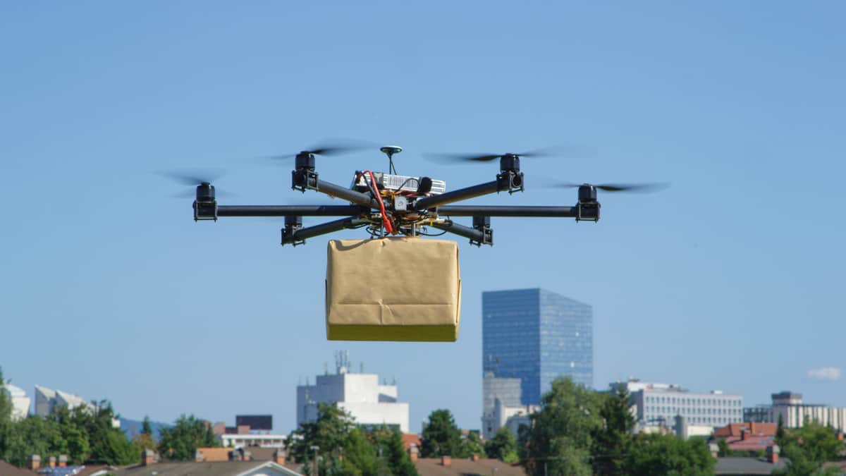 A five-rotor drone lifts a package into the air.