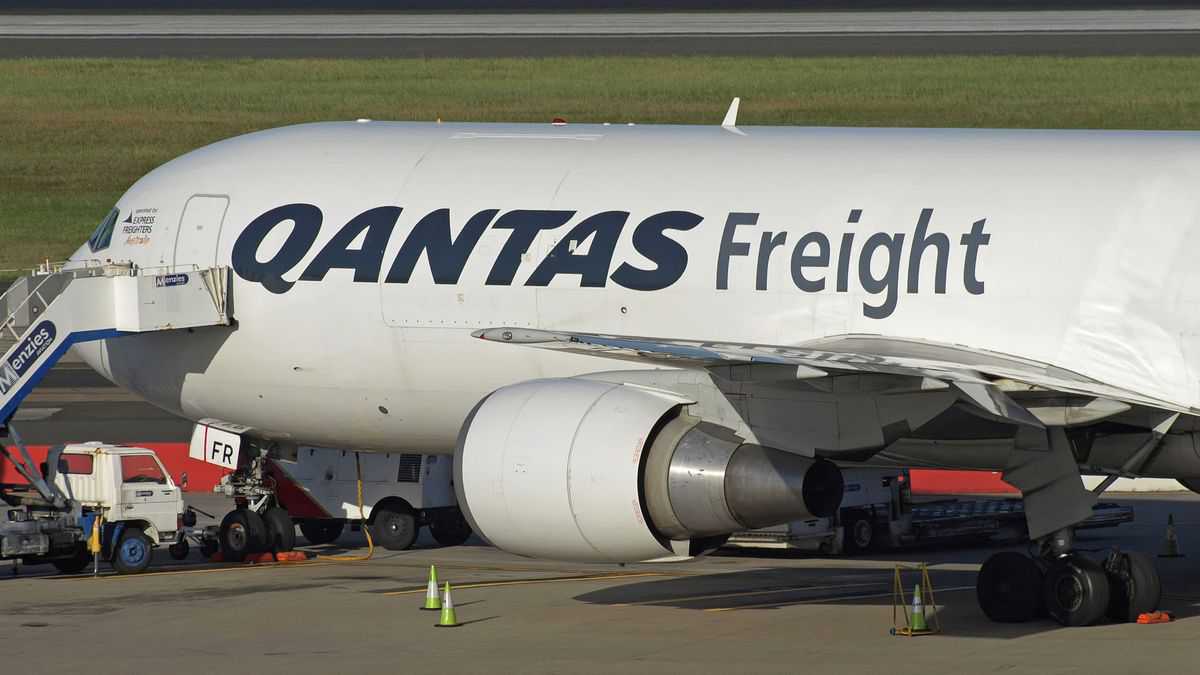 A white Qantas Freight jet with black and red lettering parked at airport.