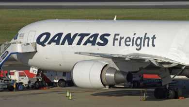 A white Qantas Freight jet with black and red lettering parked at airport.