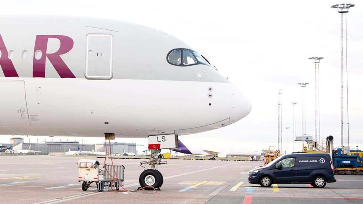 The front end, nose of a a grey plane with white underbelly, shot from the side with a blue van parked facing the plane after arriving at airport.