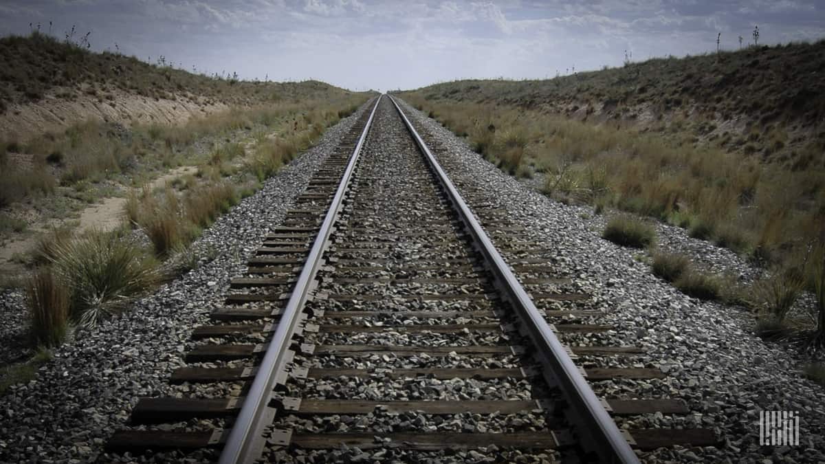 A photograph of a railroad track in a field.