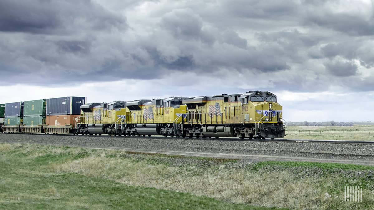 A photograph of a Union Pacific train hauling intermodal containers across a field.