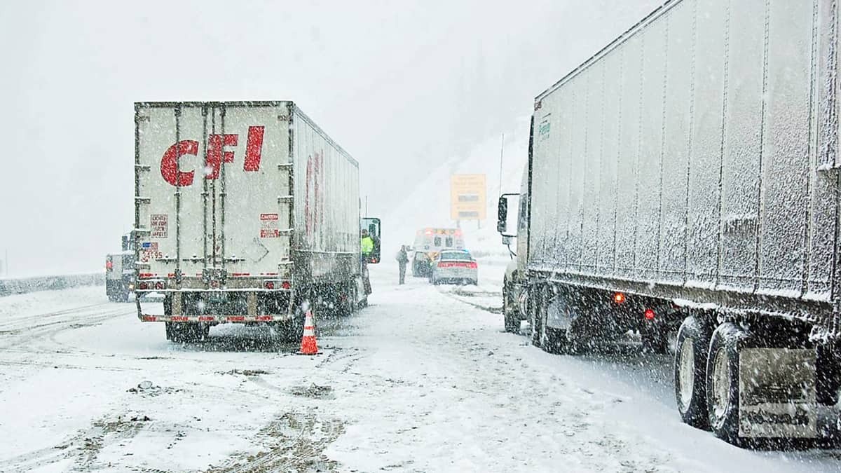 Tractor-trailers stopped on a snowy Colorado highway.