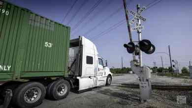 A photograph of a truck at a railroad crossing.