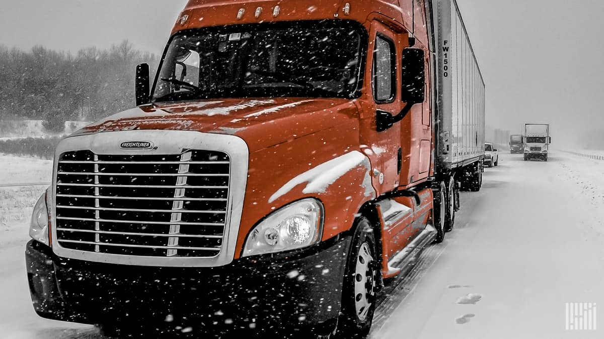 Tractor-trailers heading down snowy highway.