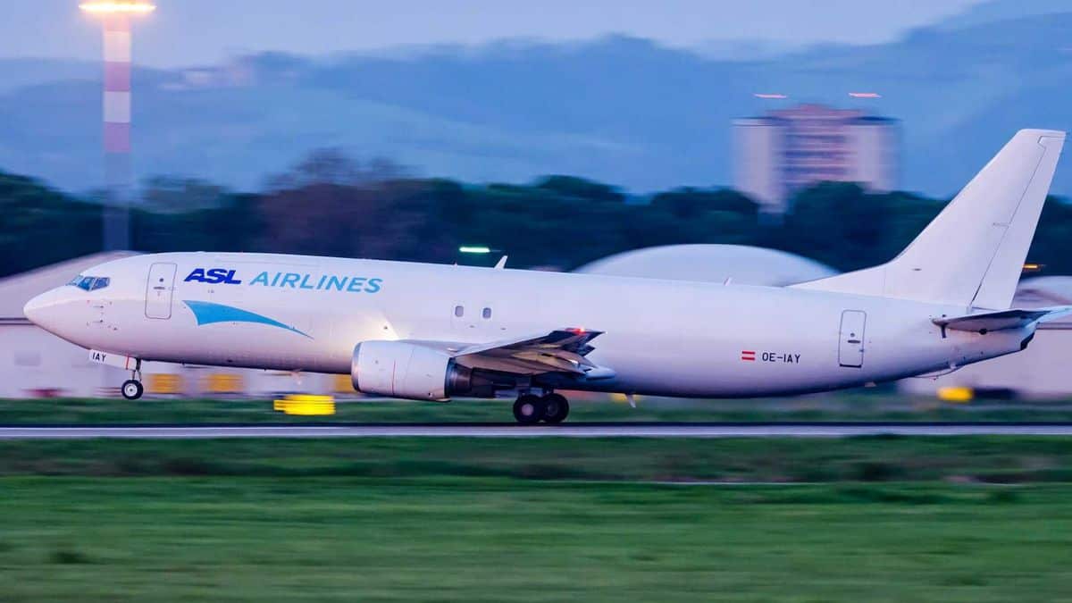 A white cargo jet touches down on runway.