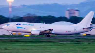 A white cargo jet touches down on runway.