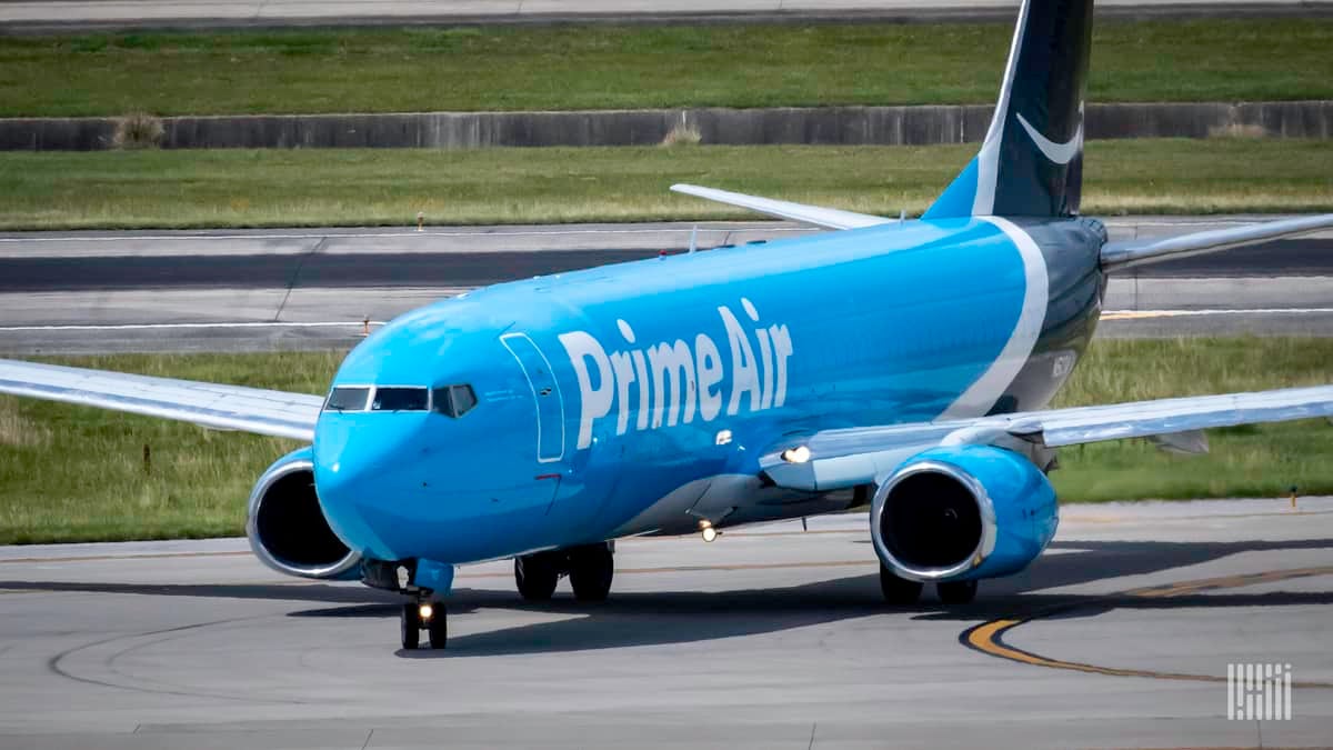 A light blue Amazon Air 737 jet moves along airport roadway.