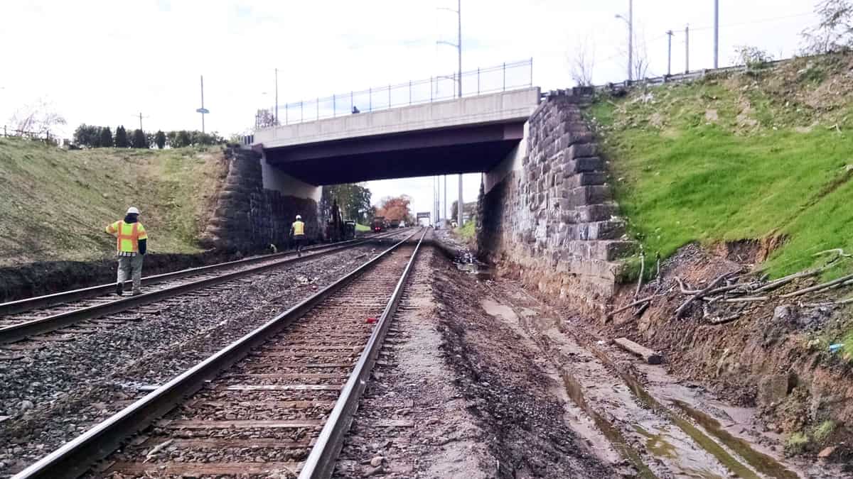 A photograph of train tracks heading under a bridge.