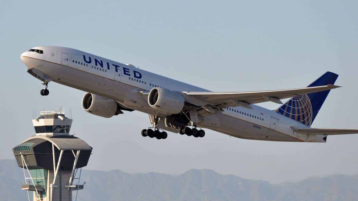 A big United Airlines jet takes off with control tower behind it.