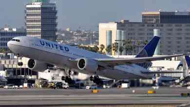 A big United Airlines jet lifts off runway on sunny day at LAX airport.