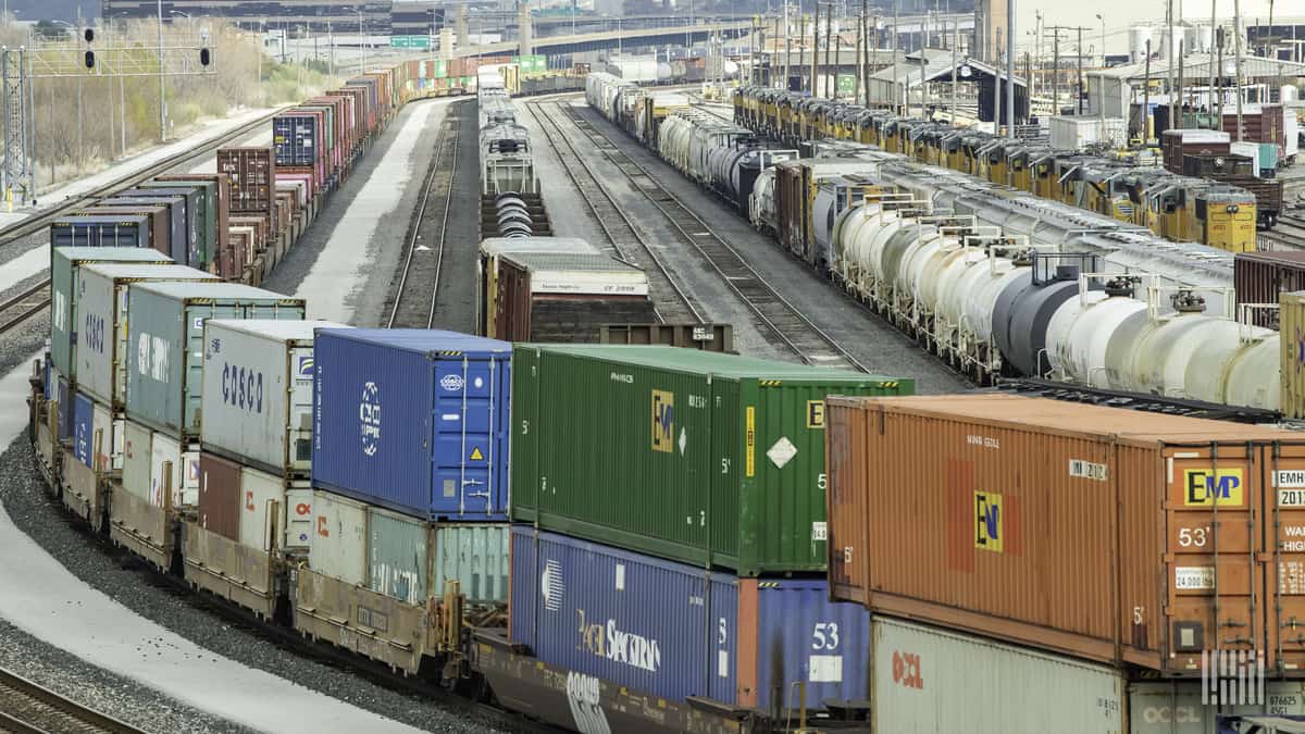 A photograph of intermodal containers and tank cars parked at a rail yard.